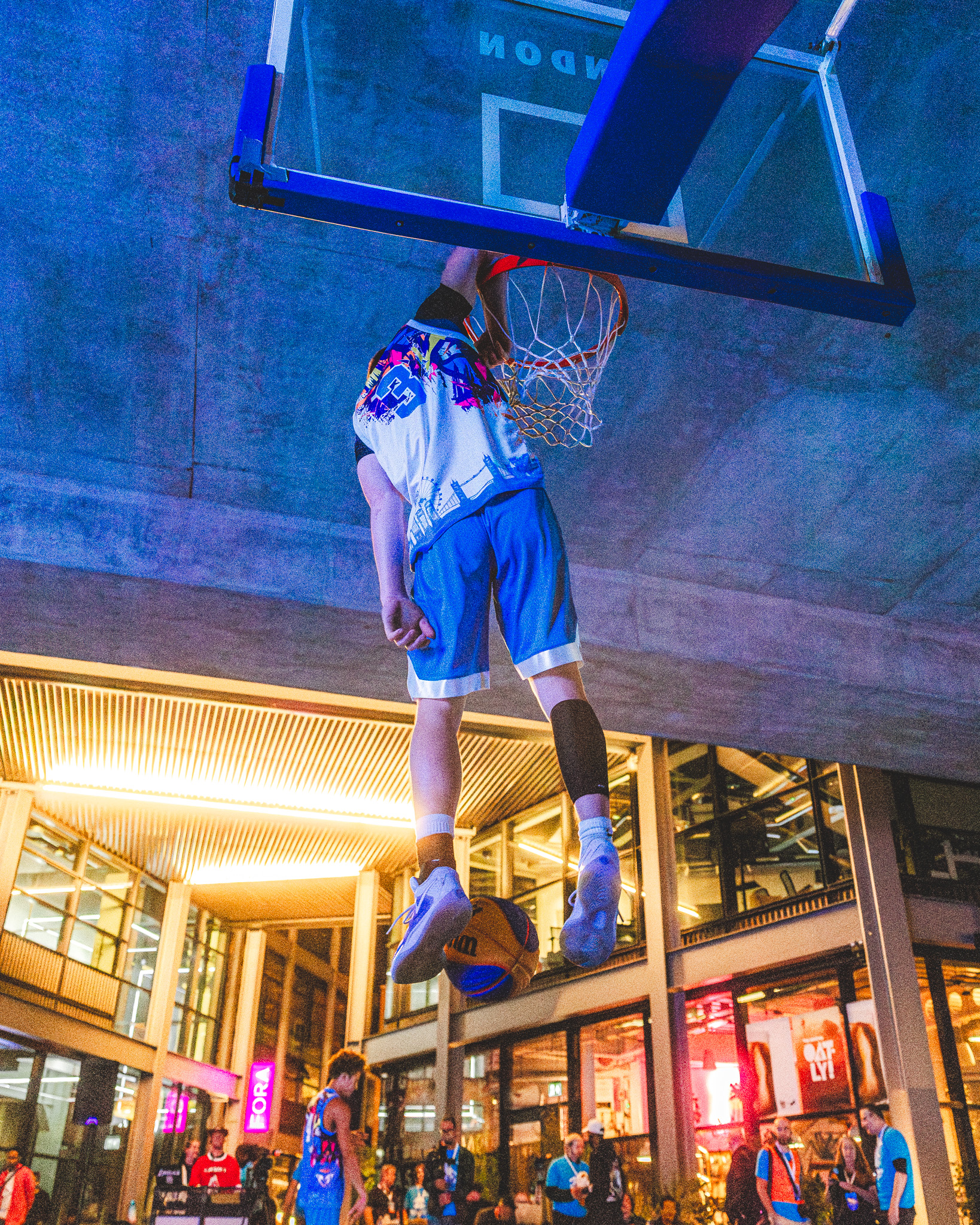 Cam Hazzard hanging on the rim after a dunk at a street court
