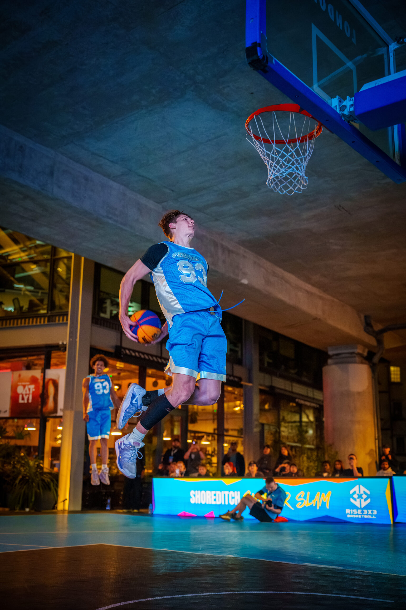 Cam Hazzard finishing a two-hand dunk at an outdoor court